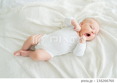 Happy baby. Cute little newborn girl with smiling face lying on bed in bedroom. Infant baby resting playing lying down on white blanket at home. Motherhood happy child childcare concept Happy baby. Cute little newborn girl with smiling face lying on bed in bedroom. Infant baby resting playing lying down on white blanket at home. Motherhood happy child childcare concept 138266760
