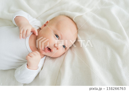 Happy baby. Cute little newborn girl with smiling face lying on bed in bedroom. Infant baby resting playing lying down on white blanket at home. Motherhood happy child childcare concept Happy baby. Cute little newborn girl with smiling face lying on bed in bedroom. Infant baby resting playing lying down on white blanket at home. Motherhood happy child childcare concept 138266763