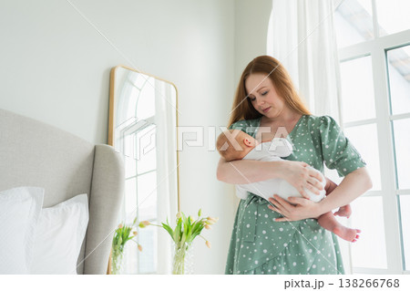 Happy family at home. Mother breastfeeding baby for health nutrition wellness. Mom nursing feeding her newborn child milk at home. Woman infant girl in white bedroom Mother hugs baby with love care Happy family at home. Mother breastfeeding baby for health nutrition wellness. Mom nursing feeding her newborn child milk at home. Woman infant girl in white bedroom Mother hugs baby with love care 138266768