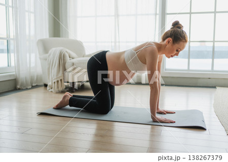 Pregnancy yoga fitness workout training. Pregnant woman practicing yoga at home. Pregnant girl doing sports exercise on yoga mat indoor. Woman with big belly have fitness training practicing asana 138267379