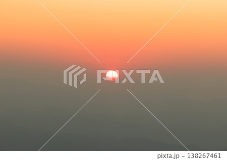 Minimal sunrise over hazy mountain layers with soft orange gradient sky, glowing sun near horizon, calm nature background, copy space for travel, meditation, wellness, design. calm, serene, peaceful 138267461