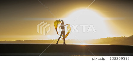 Woman dancing with flowing fabric expressing freedom at sunset 138269555