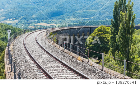 Curving railway viaduct crossing a mountain valley 138270541