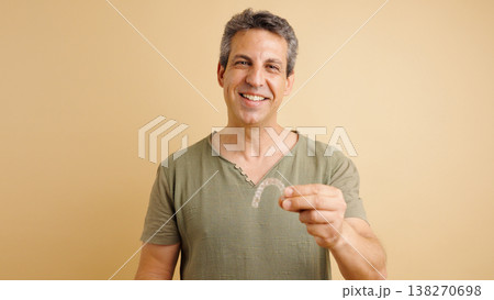 Smiling man presenting transparent dental aligner for teeth correction Smiling man presenting transparent dental aligner for teeth correction 138270698