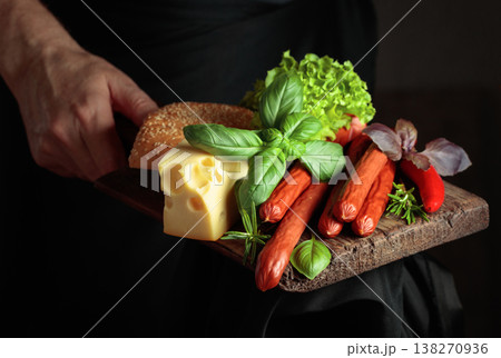 Thin smoked sausages with cheese, bread, and greens. Thin smoked sausages with cheese, bread, and greens. 138270936