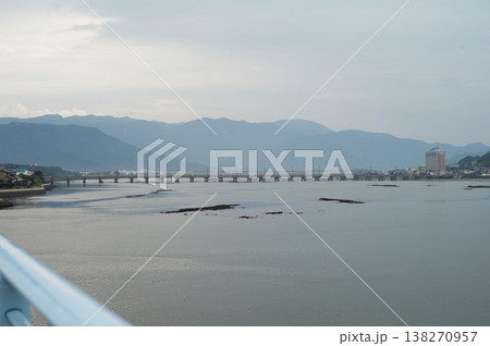 Long cement bridge across the sea with layers of mountain in background 138270957