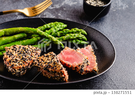 Tuna steak fried in sesame seeds served with asparagus. 138271551