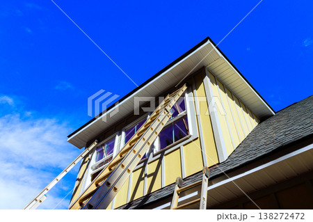 Workers are using ladders to reach upper part of house to carry out maintenance during installing hardie siding panels Workers are using ladders to reach upper part of house to carry out maintenance during installing hardie siding panels 138272472