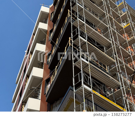 High building under construction with scaffolding and crane against blue sky. Urban development, architecture progress, engineering process, infrastructure growth, city expansion, modern industry High building under construction with scaffolding and crane against blue sky. Urban development, architecture progress, engineering process, infrastructure growth, city expansion, modern industry 138273277