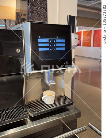 Coffee machine dispensing drink into white cup on metal grid surface. Morning routine, self service, quick break, urban convenience, everyday habit, modern appliance usage 138273282