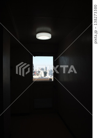 マンション共用廊下の突き当たりにある窓と天井照明、窓外に広がる街並み マンション共用廊下の突き当たりにある窓と天井照明、窓外に広がる街並み 138273380