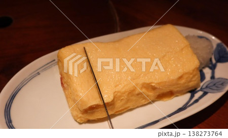 close up of rectangular Japanese rolled egg omelette (Tamagoyaki) on a plate with copy space. Cutting it to pieces with a knife 138273764