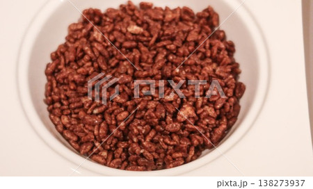 White bowl filled with chocolate puffed rice cereal granola, glossy breakfast texture with rich brown coating with copy space White bowl filled with chocolate puffed rice cereal granola, glossy breakfast texture with rich brown coating with copy space 138273937