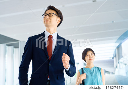 輝く未来を見据えてオフィスビルを歩く自信に満ちたビジネスマンとビジネスウーマン 輝く未来を見据えてオフィスビルを歩く自信に満ちたビジネスマンとビジネスウーマン 138274374