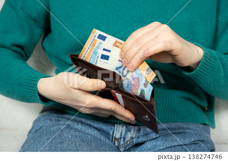 Hands put the euro banknotes in the wallet. Concepts of financial security, liquidity, and economic stability with paper currency. 138274746