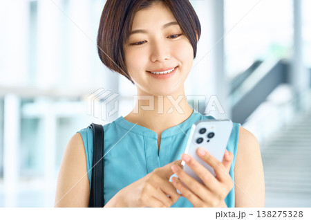 スマートフォンを操作して笑顔を見せる20代の日本人女性 138275328