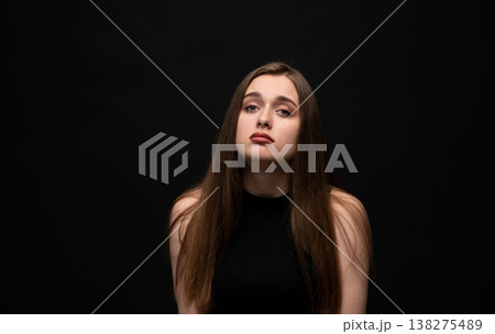 Young woman expressing sorrow and sadness, portraying feelings of loneliness, depression, and grief on a dark background Young woman expressing sorrow and sadness, portraying feelings of loneliness, depression, and grief on a dark background 138275489