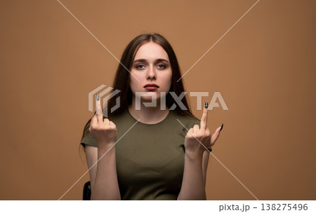 Young woman showing middle finger gesture with both hands expressing anger and frustration on a brown background Young woman showing middle finger gesture with both hands expressing anger and frustration on a brown background 138275496