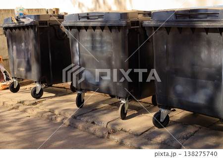 Plastic trash containers in a residential area. Row of black trash containers Plastic trash containers in a residential area. Row of black trash containers 138275740