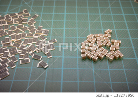 SMD electronic components comparison on green cutting mat, resistors and capacitors 138275950
