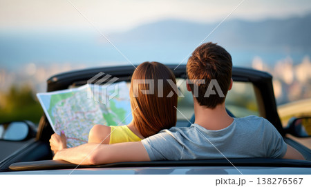 Happy young couple sitting in convertible car holding map planning road trip route 138276567