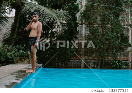 Adult man jumping into swimming pool in garden Adult man jumping into swimming pool in garden 138277535
