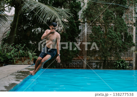 Man enjoying refreshing swim in outdoor pool 138277538