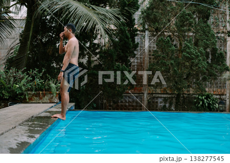 Man diving into pool surrounded by greenery 138277545