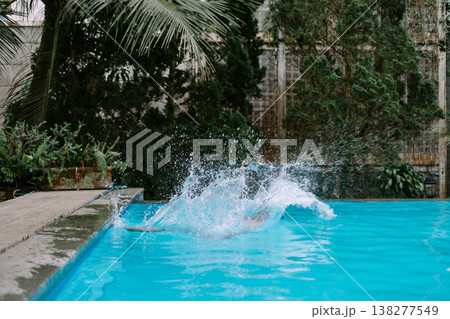 Casual pool activity man jumping into water Casual pool activity man jumping into water 138277549