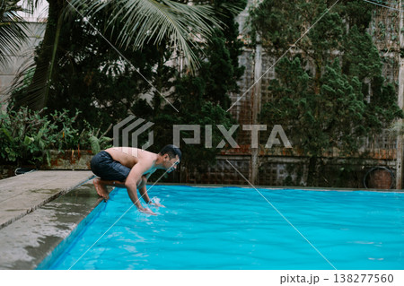 Southeast Asian man enjoying water splash in pool 138277560
