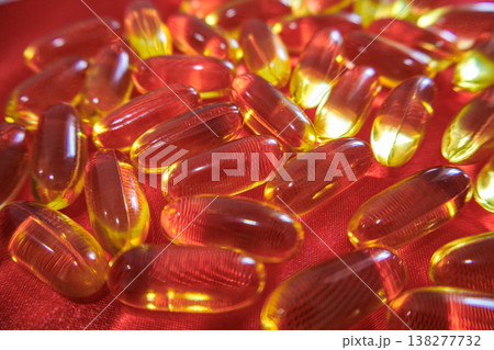 Close up of fish oil capsules scattered on red fabric. Omega 3 supplements, healthy lifestyle and nutrition concept with bright glossy softgel pills. 138277732