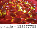 Soft focus fish oil capsules on red background. Omega 3 supplements and wellness concept with glowing translucent softgel pills. 138277733