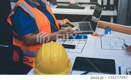 engineer and an architect reviewing blueprints and construction plans together at a bustling construction site engineer and an architect reviewing blueprints and construction plans together at a bustling construction site 138277897