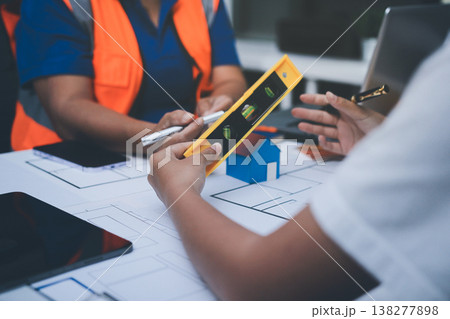 engineer and an architect reviewing blueprints and construction plans together at a bustling construction site engineer and an architect reviewing blueprints and construction plans together at a bustling construction site 138277898