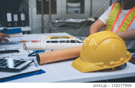 engineer and an architect reviewing blueprints and construction plans together at a bustling construction site 138277906