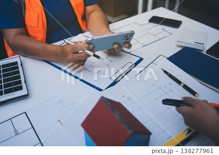 engineer and an architect reviewing blueprints and construction plans together at a bustling construction site 138277961
