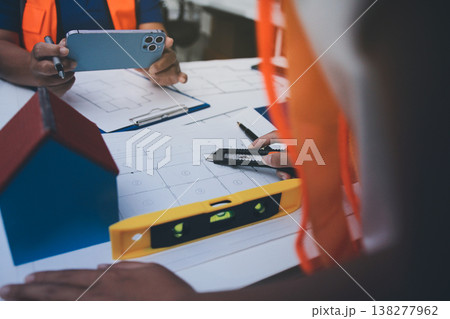 engineer and an architect reviewing blueprints and construction plans together at a bustling construction site 138277962