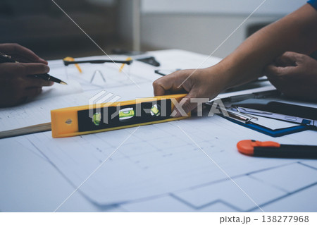 engineer and an architect reviewing blueprints and construction plans together at a bustling construction site engineer and an architect reviewing blueprints and construction plans together at a bustling construction site 138277968