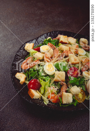 caesar salad with tiger prawns, shrimp salad, lettuce leaves, quail eggs, cherry tomatoes, parmesan cheese, on a black plate, 138278890