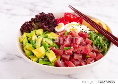 Fresh poke bowl, with tuna, avocado, and vegetables, served on a white plate Fresh poke bowl, with tuna, avocado, and vegetables, served on a white plate 138278933