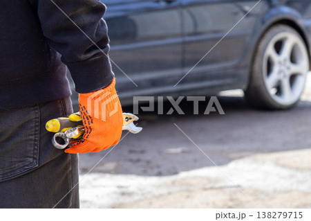 Focused mechanic prepares to fix a vehicle, holding a wrench and wearing bright gloves, surrounded by a vibrant garage atmosphere Focused mechanic prepares to fix a vehicle, holding a wrench and wearing bright gloves, surrounded by a vibrant garage atmosphere 138279715