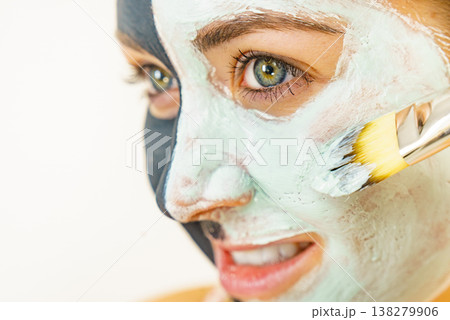 Female applying green mud facial mask 138279906