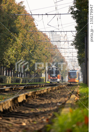 Tram urban public transport rides on rails with green grass and trees. transportation of passengers. Tram urban public transport rides on rails with green grass and trees. transportation of passengers. 138279947