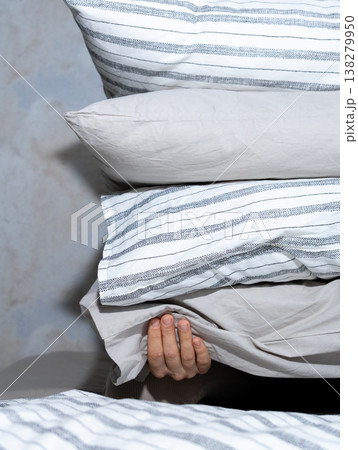 woman holds stack of pillows with her hands while sitting on the bed. rest and restful sleep. woman holds stack of pillows with her hands while sitting on the bed. rest and restful sleep. 138279950