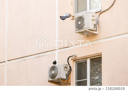 air conditioner is installed on facade of the building. air conditioner compressor is on wall. 138280010