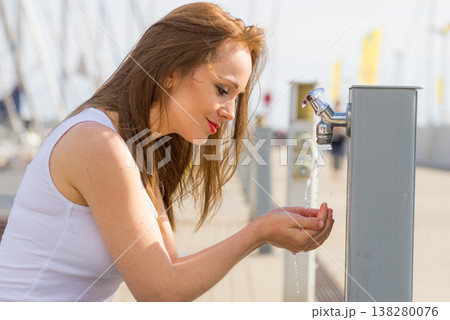Woman drinking water from tap in marina. 138280076