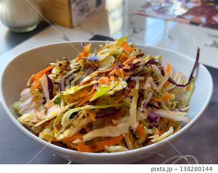 Mixed cabbage and carrot salad in a white bowl with glossy dressing and crisp texture. Fresh side dish, healthy restaurant serving and colorful vegetable accompaniment for everyday meals Mixed cabbage and carrot salad in a white bowl with glossy dressing and crisp texture. Fresh side dish, healthy restaurant serving and colorful vegetable accompaniment for everyday meals 138280144