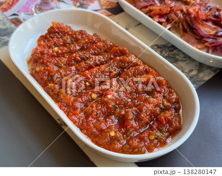 Spicy Turkish ezme spread served in a white dish with rich red pepper and tomato texture. Traditional meze appetizer, restaurant menu presentation and savory condiment for grilled dishes Spicy Turkish ezme spread served in a white dish with rich red pepper and tomato texture. Traditional meze appetizer, restaurant menu presentation and savory condiment for grilled dishes 138280147
