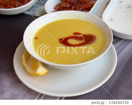 Creamy lentil soup served with paprika butter swirl and lemon on a white plate. Traditional Turkish comfort food, restaurant starter presentation and warm nourishing meal concept Creamy lentil soup served with paprika butter swirl and lemon on a white plate. Traditional Turkish comfort food, restaurant starter presentation and warm nourishing meal concept 138280150