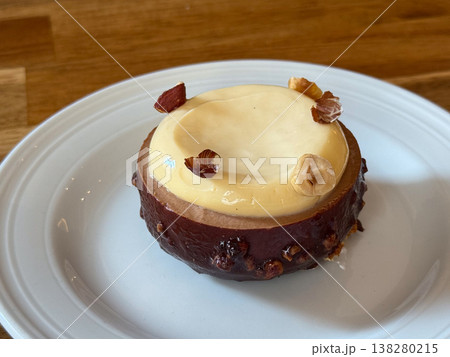 Hazelnut dessert pastry with glossy cream topping served on a white plate in close view. Gourmet patisserie presentation, menu styling and indulgent cafe confection for elegant food branding Hazelnut dessert pastry with glossy cream topping served on a white plate in close view. Gourmet patisserie presentation, menu styling and indulgent cafe confection for elegant food branding 138280215